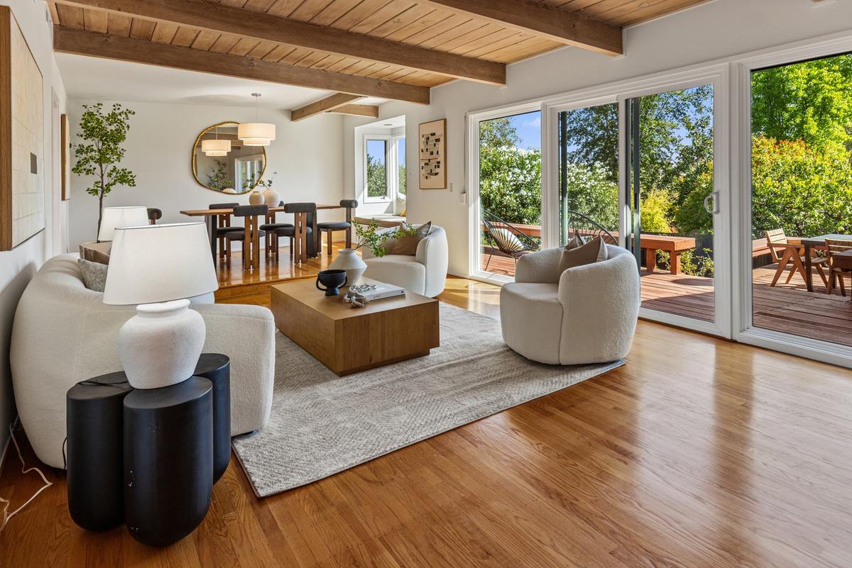 Living room with a beamed wood ceiling, hardwood floors and sliding glass doors to the deck